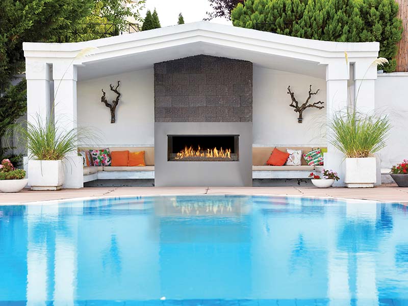Outdoor gas fireplace overlooking pool with cabanas