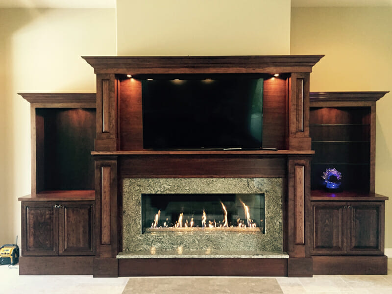 Wooden fireplace flanked by cabinets on each side