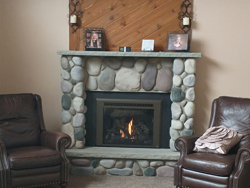 Fireplace with pictures on mantle and leather chairs on each side