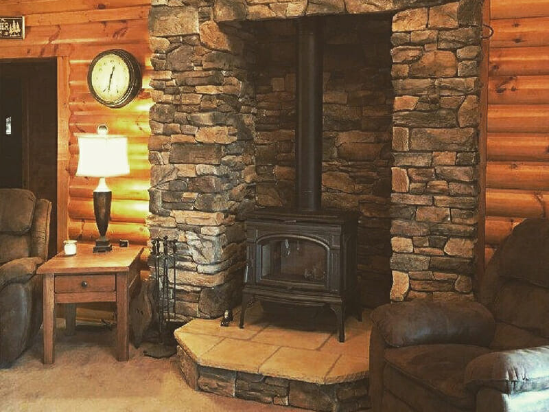 Stove in brick fireplace with rustic wooden walls